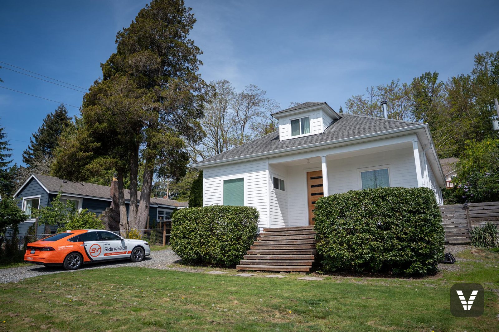 Wide view of the re-sided home in spring sun