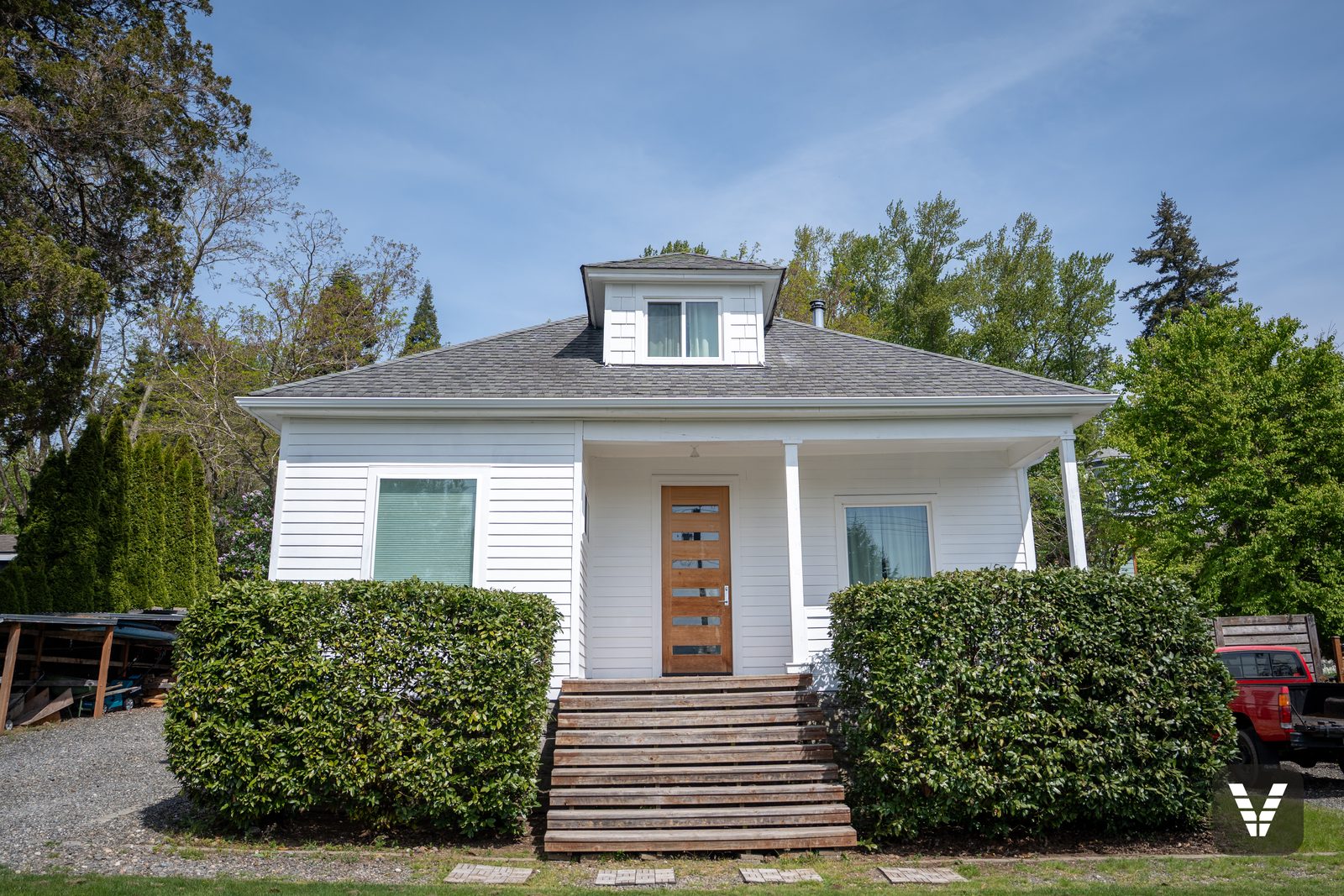 The 1914 bungalow after its re-side — white HardiePlank at a 5-inch reveal, shingled cupola dormer, original porch