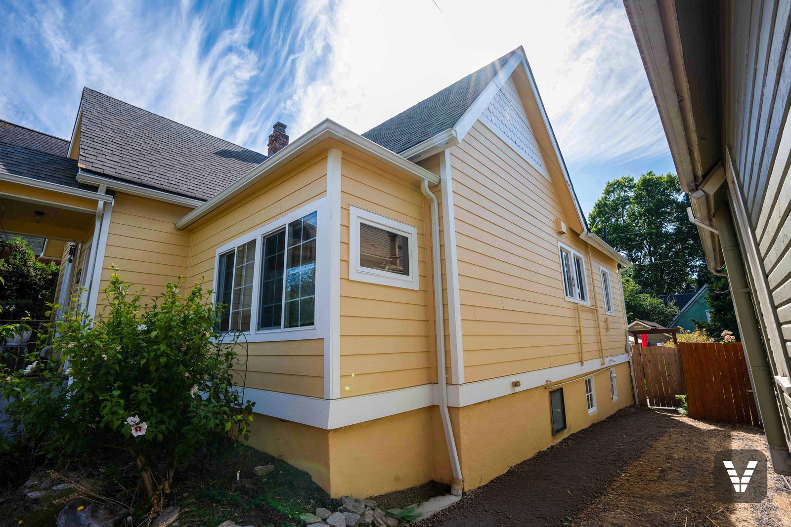 The side yard corner — new lap, big grid windows, and the fresh white belly-board line