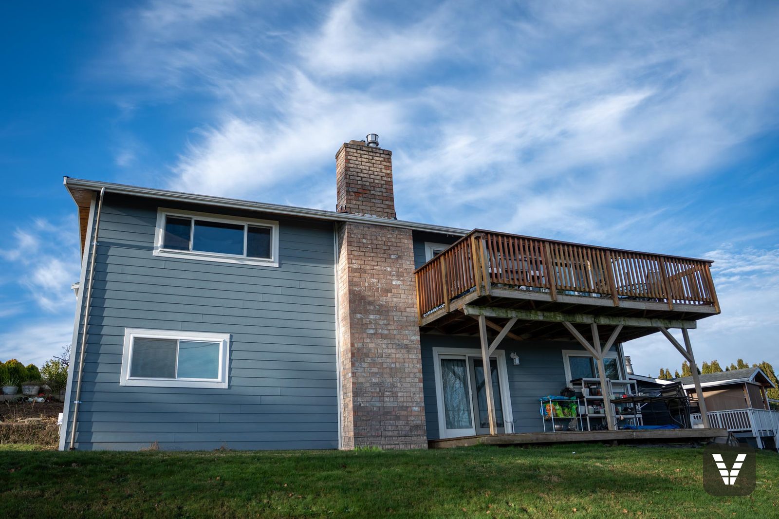 The rear elevation — Boothbay Blue against the brick chimney and the upper deck