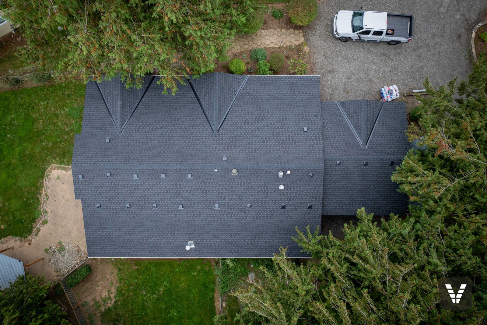 The crew truck in the driveway below a finished Lynden roof — the licensed, findable kind of contractor