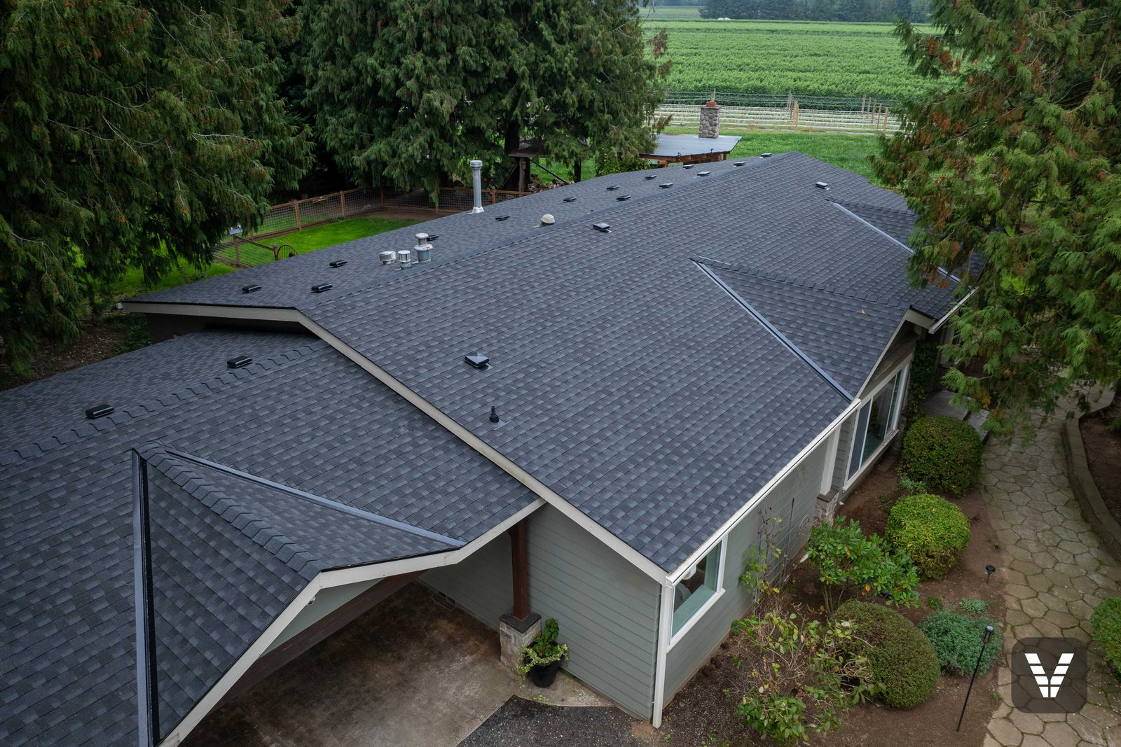 Aerial view of a completed GAF Timberline HDZ roof in Charcoal on a Lynden rambler with berry fields and the Cascades behind — Siding & Window Vault project in Lynden, WA