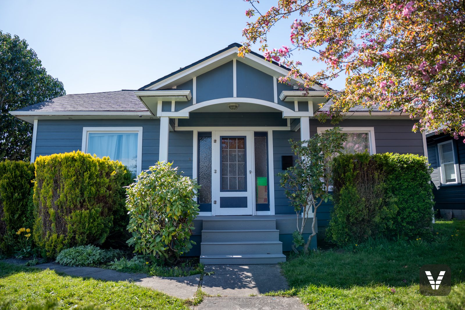 The 1912 bungalow after its re-side — Evening Blue James Hardie lap, Arctic White trim, and the original arched portico preserved