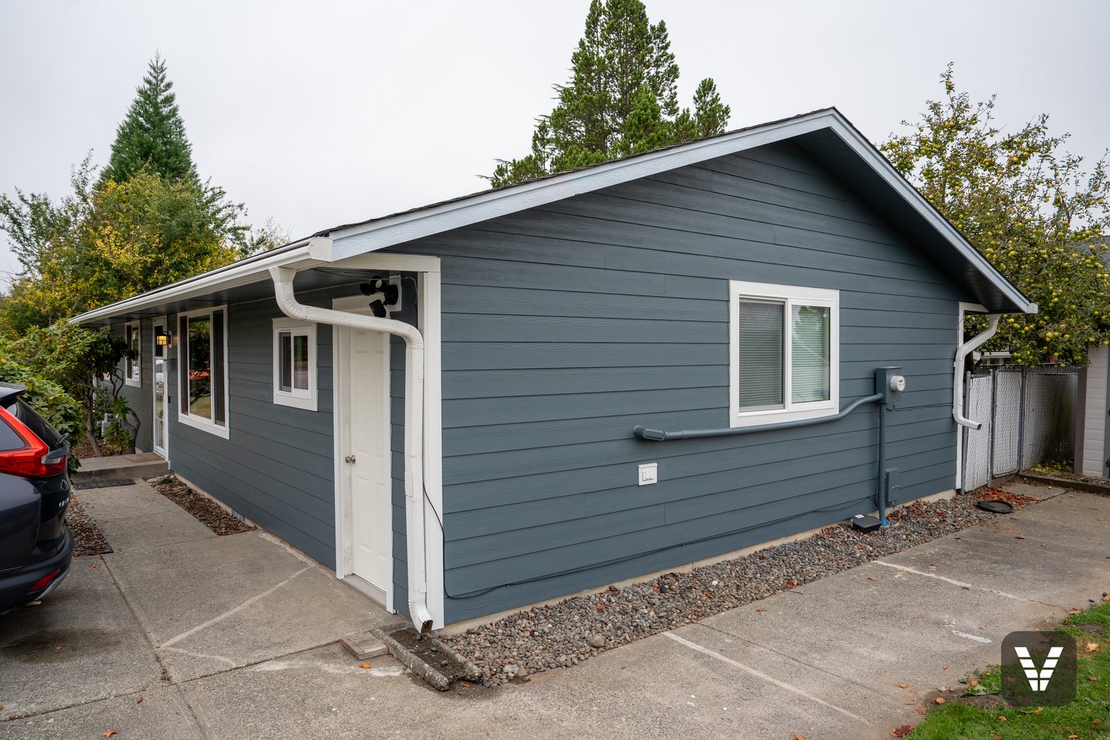 Driveway side of the finished home — Evening Blue HardiePlank with Arctic White trim around the side door and the gable window