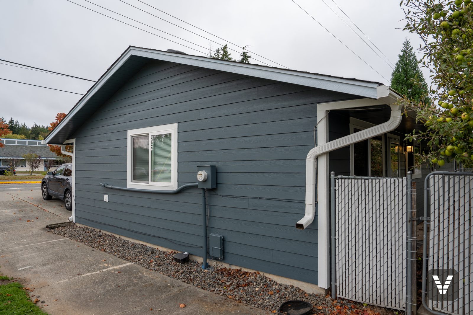 The side gable from the back gate — new lap siding, with the meter conduit painted to match