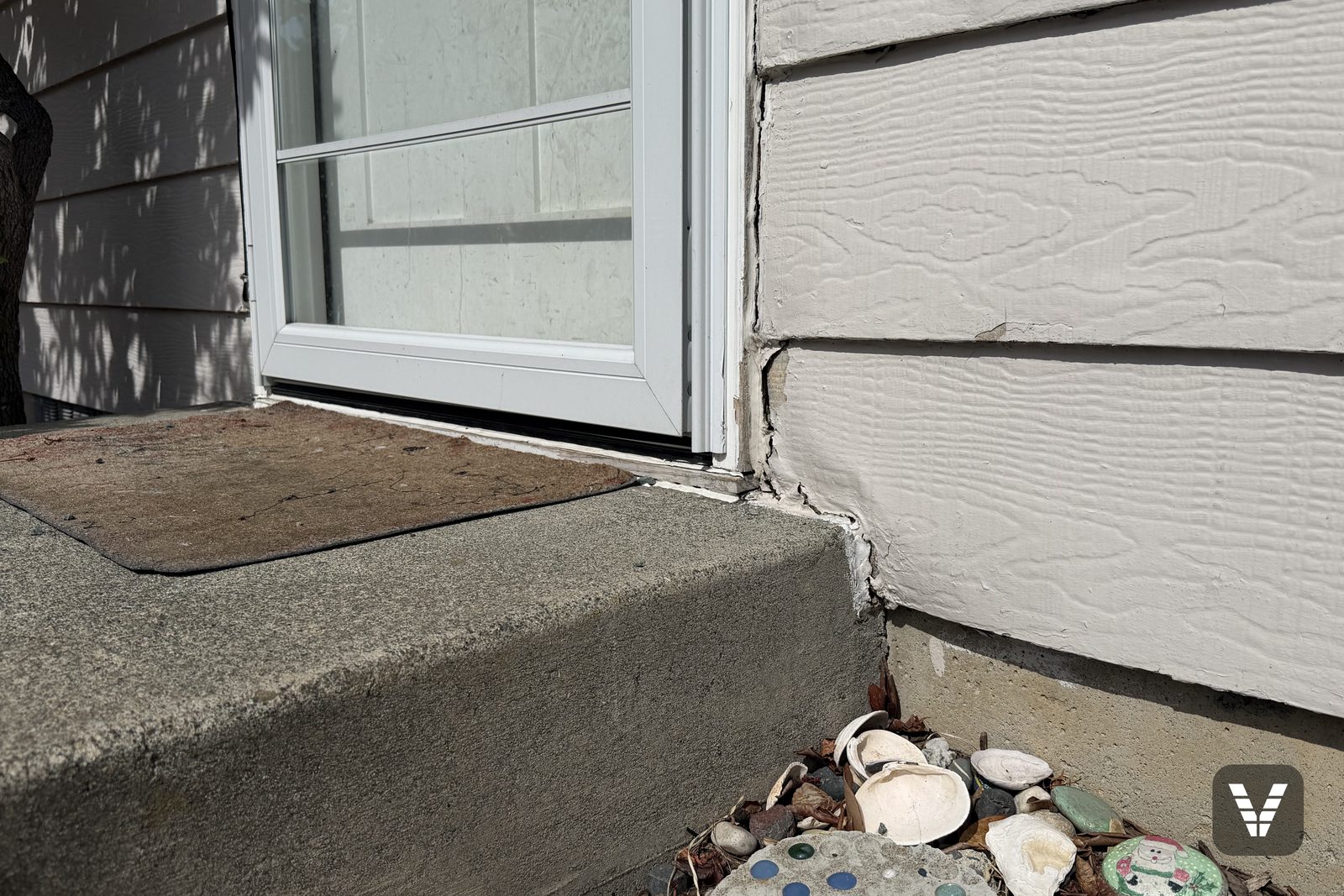 Cracked, swollen lap siding beside a front step and door, the kind of damage a coat of paint can't fix