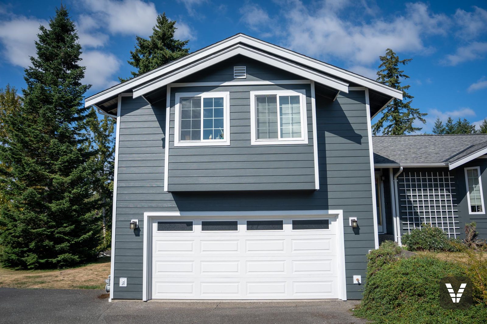 Garage wing of a Bellingham home with new colonial-grid windows trimmed in white, set in Iron Gray James Hardie lap siding