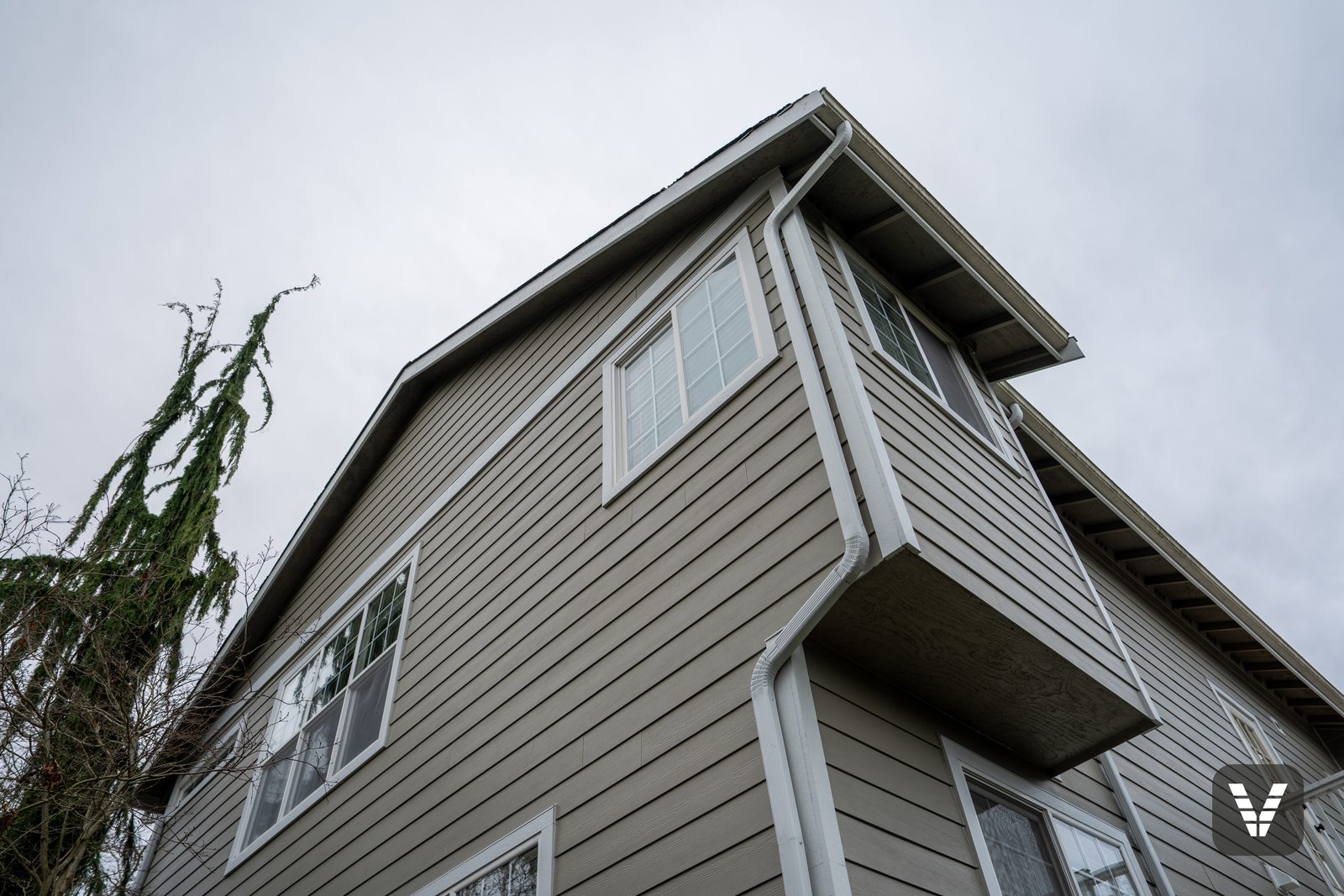 Looking up the corner — clean lap lines, painted eaves, and downspout — Siding & Window Vault project in Anacortes, WA