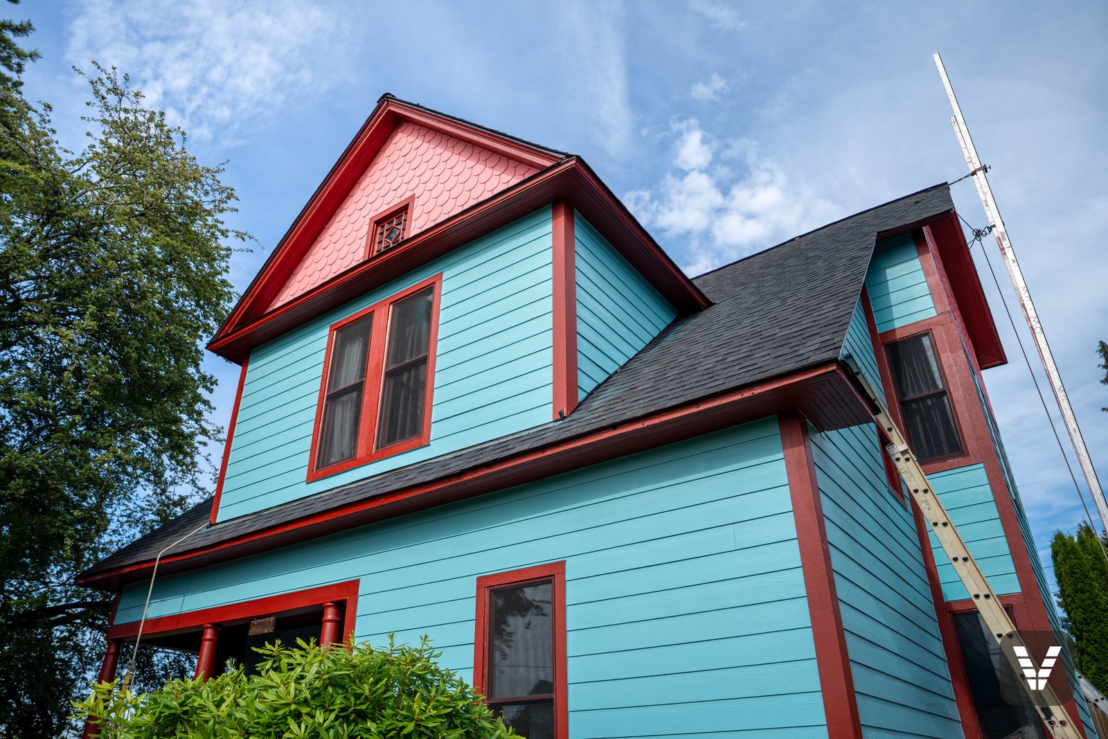 Looking up at the gable — fishscale scallops over turquoise lap in the final days of painting