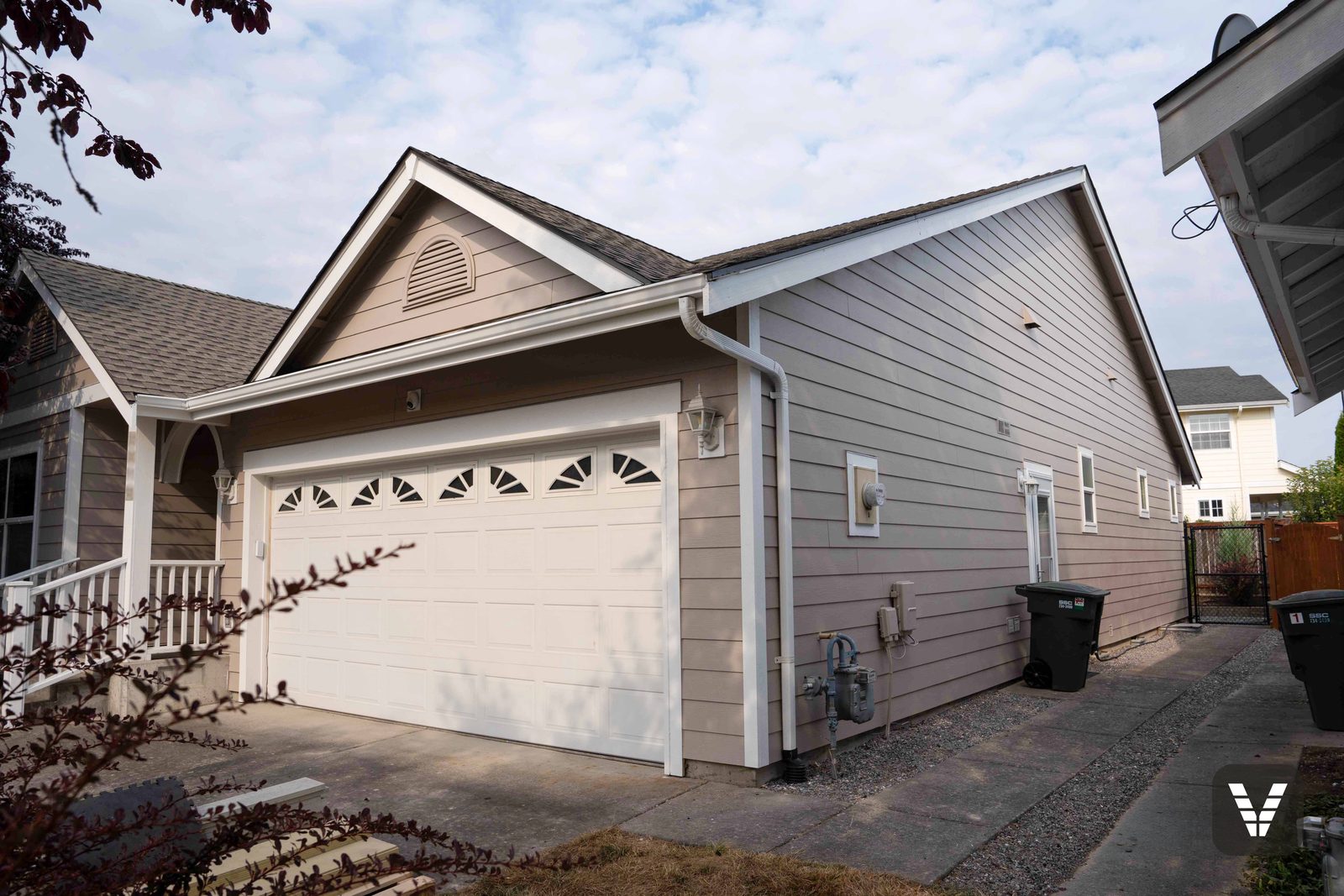 The garage wing and side path — fresh lap, painted gutters, and the lantern sconces back on their new fiber-cement blocks