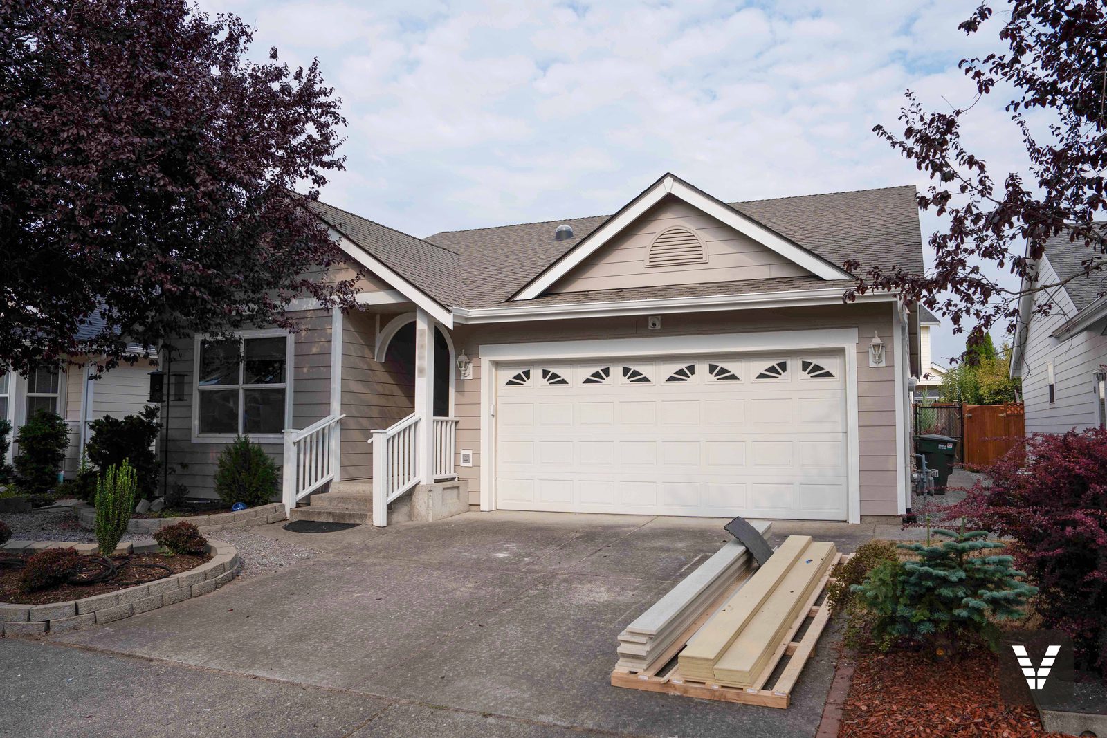 Completed James Hardie re-side painted warm taupe with white trim on a Bellingham rambler, materials pallet still in the driveway