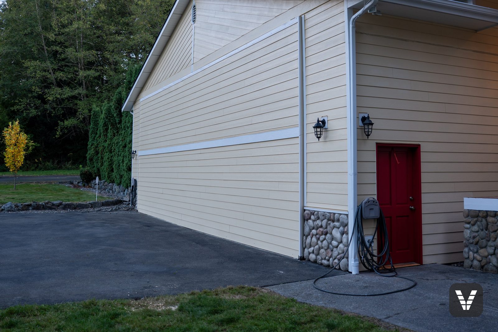 Hangar side door in red against fresh lap siding and rock skirt