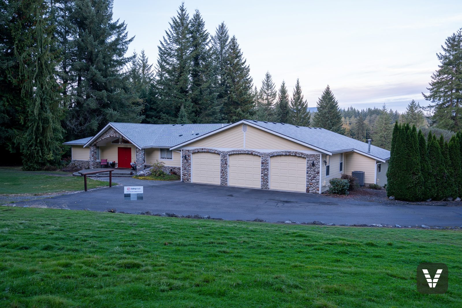 The full front — three-car garage, rock arches, and the re-sided, repainted main house