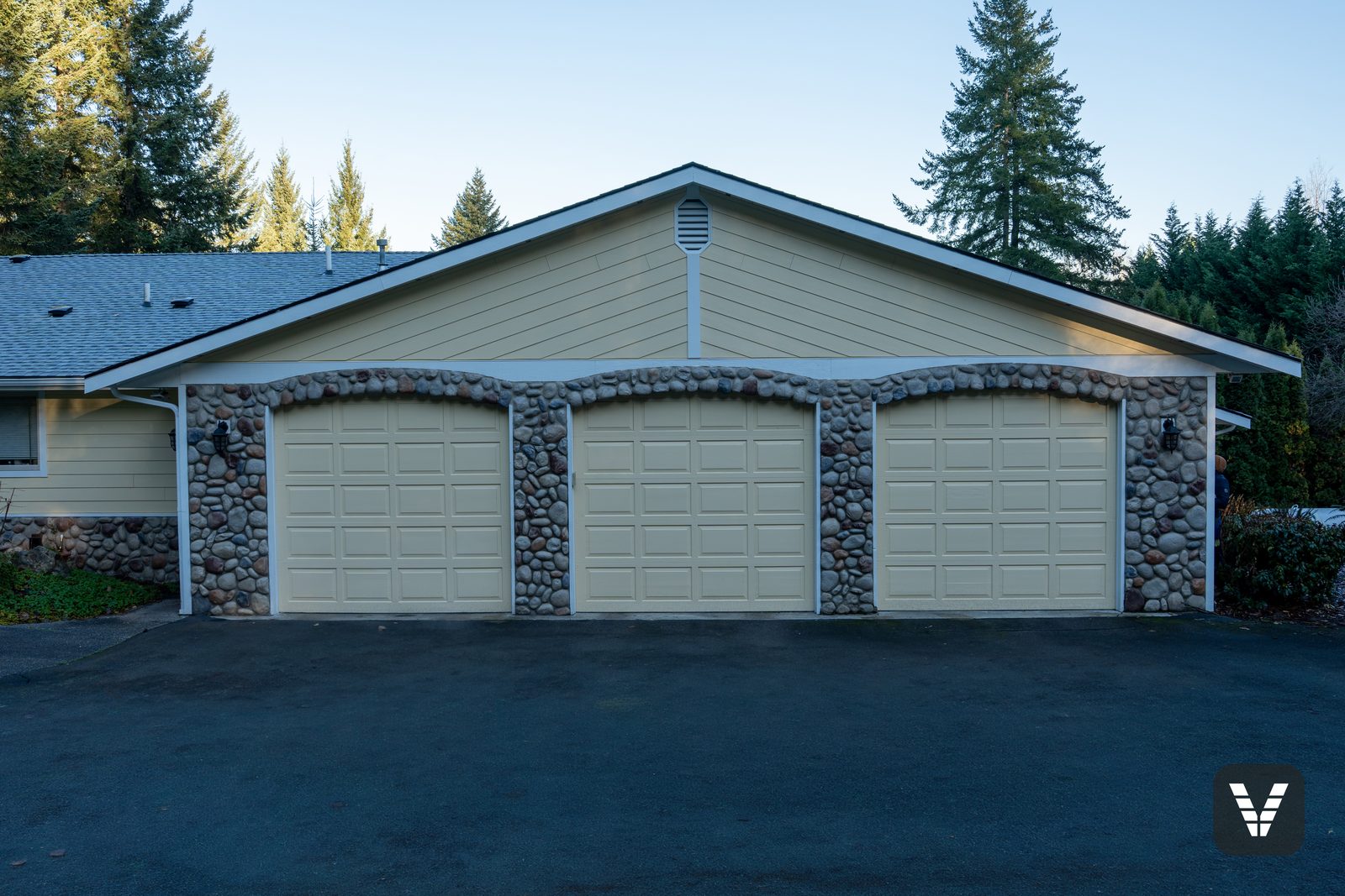 Three-car garage with river-rock arches, doors puttied and painted