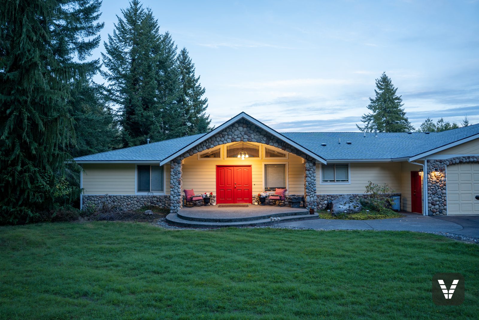 Finished entry at twilight — red double doors, river-rock columns, and fresh yellow HardiePlank in Lake Stevens, WA — Siding & Window Vault project in Lake Stevens, WA